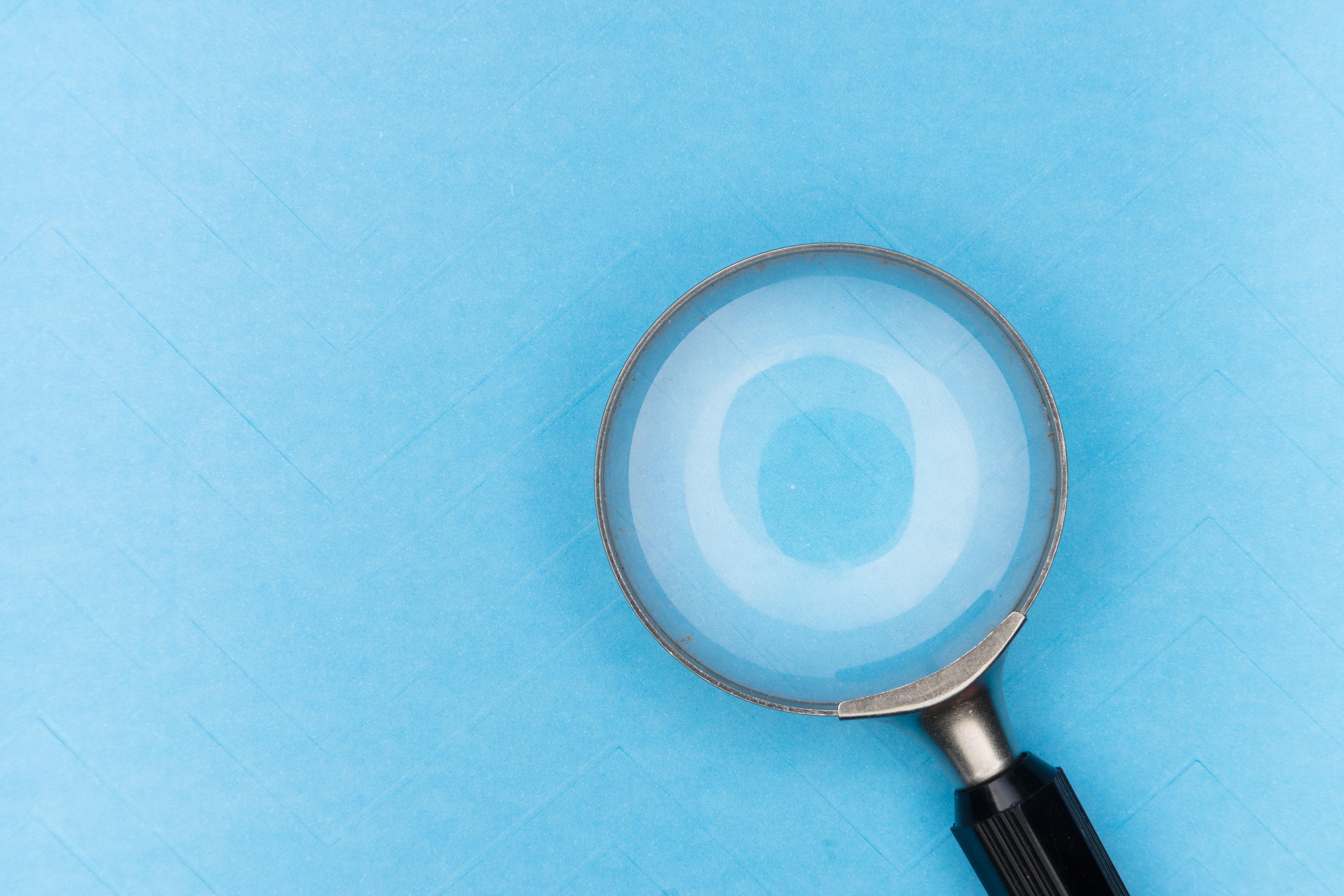 A magnifying glass on a blue surface, by Markus Winkler.